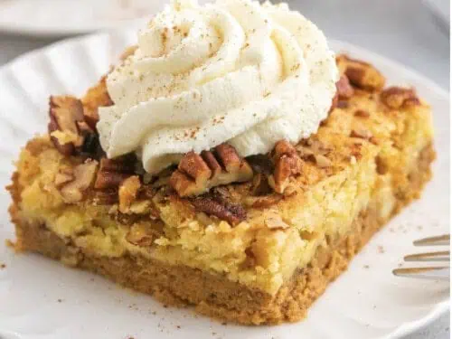 pumpkin dump cake serving on a plate, topped with whipped cream.